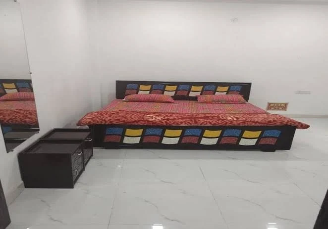 Guest room with a colorful bed and white tiled flooring.